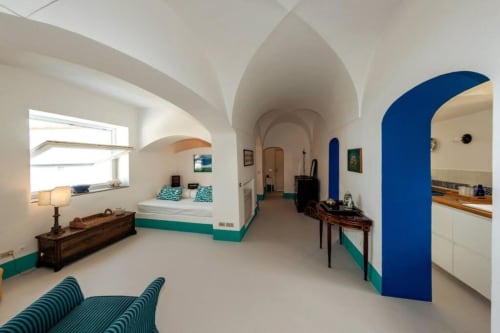 Suite moderna di Capri con soffitti a volta, accenti turchesi, letto, angolo cottura e porte ad arco