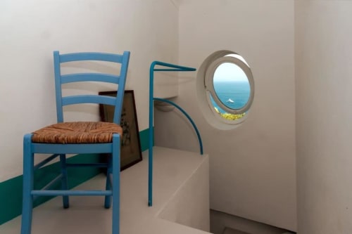 Sedia scala blu con seduta intrecciata affacciata su oblò con vista mare a La Conciergerie Capri