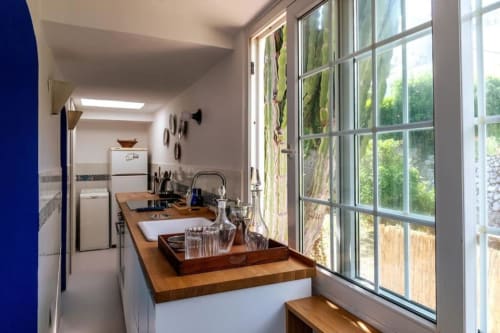 Cucina moderna con piano di lavoro in legno, elettrodomestici in acciaio inox e ampi affacci sul giardino di Capri presso La Conciergerie.