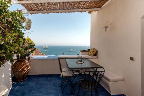 Terrazza fronte mare a La Conciergerie Capri con vista sul Mediterraneo, tavolo da pranzo e piante da giardino costiero