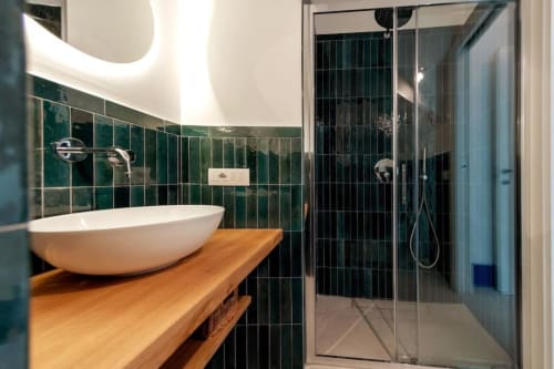Bagno moderno di La Conciergerie Capri con piastrelle verdi, lavabo bianco su mobile in legno e doccia a pioggia