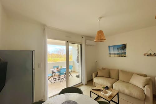 Accogliente appartamento a Résidence Marina di Bravone con divano beige, accesso alla terrazza e vista sul mare