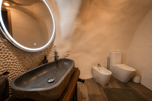 Banheiro moderno em Jardines de Ifonche com pia de pedra, bidê, vaso sanitário e espelho iluminado em Santa Cruz de Tenerife