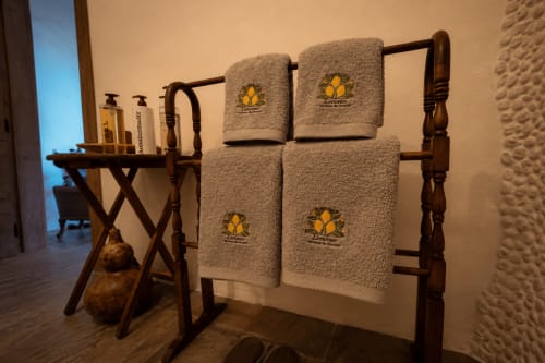 Toalheiro de banheiro com quatro toalhas bordadas e prateleira de artigos de higiene no quarto Limones em Jardines de Ifonche, Tenerife
