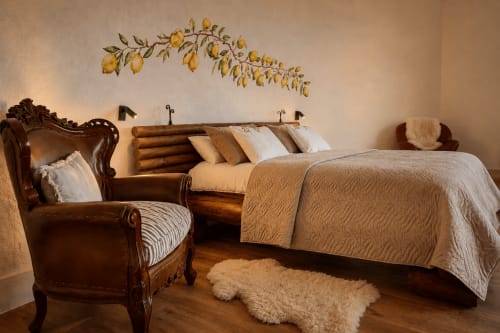 Limones room at Jardines de Ifonche with leather armchair, wooden log bed, beige bedding, and lemon wall art in Santa Cruz de