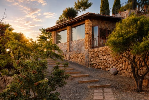 Arquitetura em pedra nos Jardines de Ifonche, Tenerife com caminho florido e vistas montanhosas ao pôr do sol