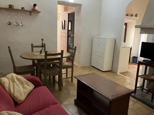 Sala de estar y comedor en la villa Casa Zarcillo de Casa Rural La Navarra, Villarrobledo, con sofá burdeos, mesa de madera y