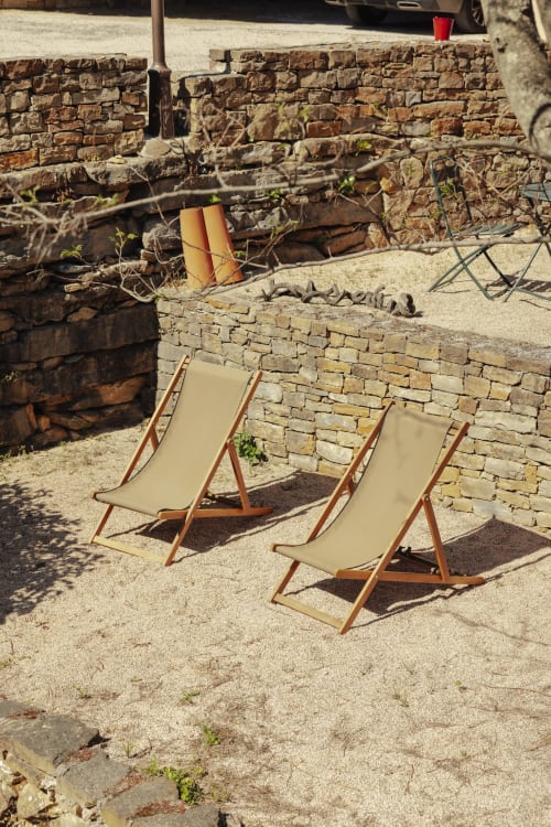 Beige deck chairs on sandy ground with stone walls at Mas Tihou garden view room in Le Beausset