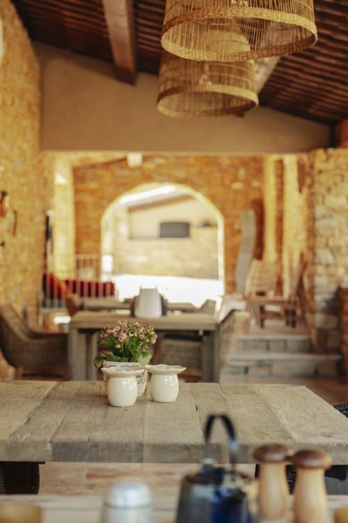 Cozy garden room at Mas Tihou B&B in Le Beausset with rustic wooden table, potted flowers, and woven pendant lamp