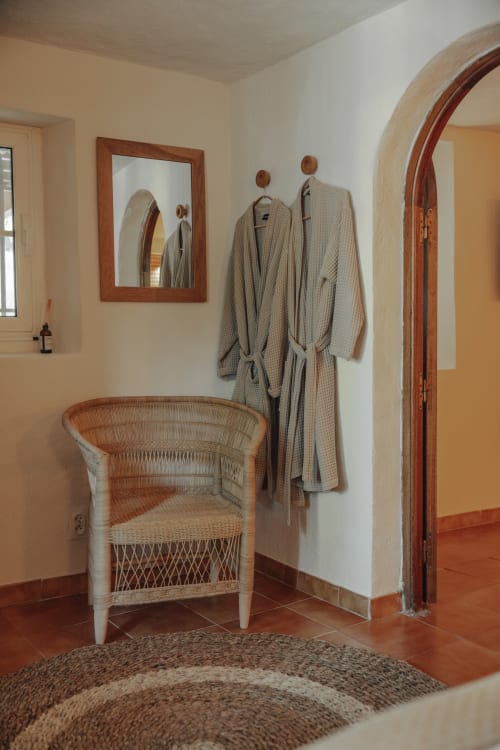Cozy room at Mas Tihou B&B in Le Beausset with wicker chair, robes, mirror and terracotta floors