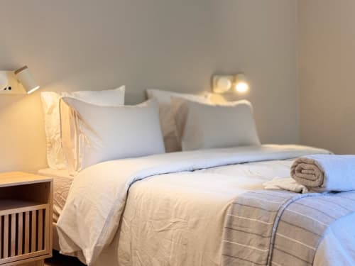 Quarto luxuoso na Quinta Do Carril com roupa de cama branca, toalha enrolada, iluminação acolhedora e vista para a piscina