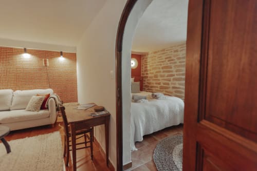 Mas Tihou bedroom suite in Le Beausset with terracotta tiles, brick accent wall, and open archway to living area