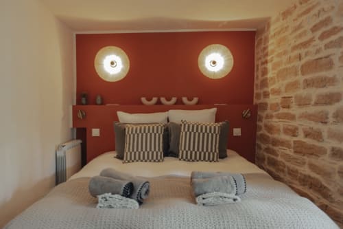 Modern bedroom at Mas Tihou B&B in Le Beausset with red accent wall, circular lights, brick wall, and striped pillows