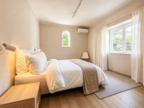 Quarto moderno e luminoso na Quinta Do Carril com roupa de cama branca, móveis em madeira e amplas janelas com vista para a natureza