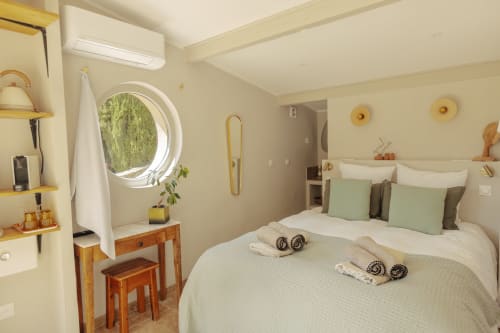 Bright bedroom at Mas Tihou B&B in Le Beausset with twin beds, round window, wooden vanity, and garden views