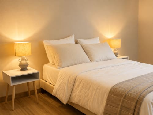 Quarto aconchegante na Quinta Do Carril com iluminação calorosa, roupa de cama creme e mesinhas de madeira no Quarto Simão