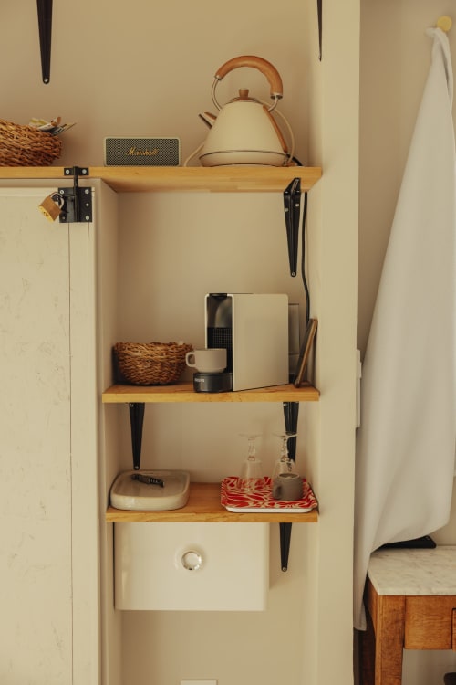 Wooden wall shelves with kettle, coffee maker, and decor in Mas Tihou's Cabanon Tihou room, Le Beausset