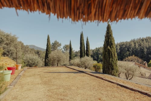 Rustic garden terrace at Mas Tihou with cypress trees, olive grove, and mountain views in Le Beausset