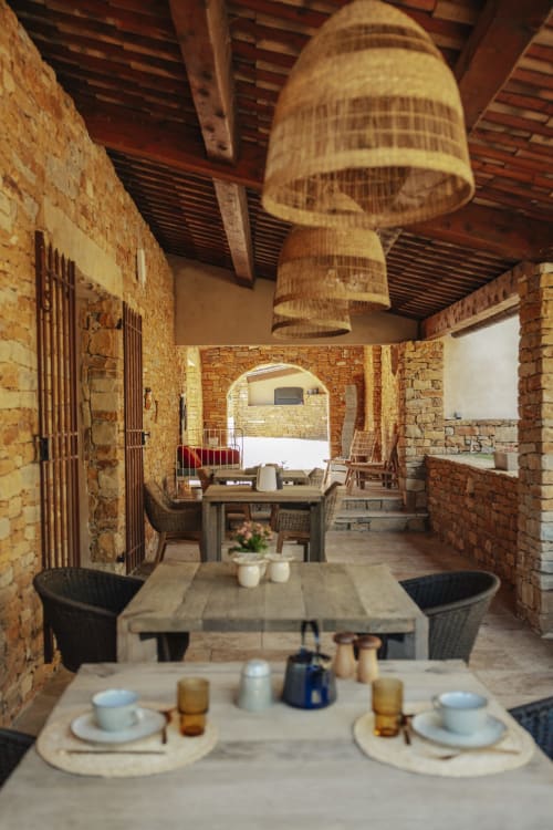 Rustic dining room at Mas Tihou B&B with exposed brick walls, woven pendant lights, and served table in Le Beausset