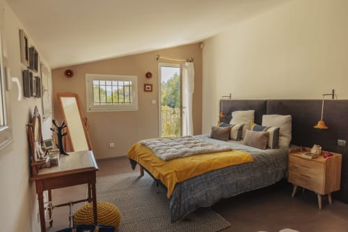 Chambre spacieuse à Mas Tihou avec vue sur le jardin, lit moderne, table de nuit en bois et accès à la terrasse