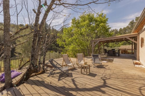 Grande terrasse en bois de la maison d'hôtes Mas Tihou avec transats, arbres et vue sur les montagnes à Le Beausset