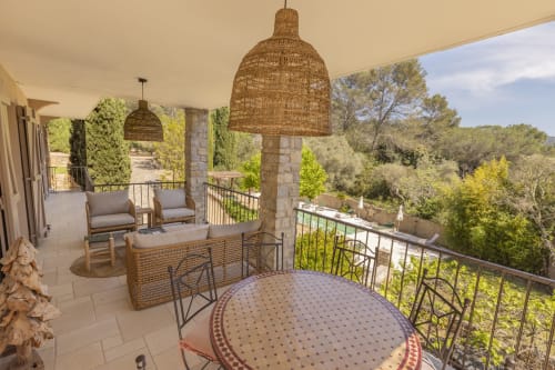 Terrasse couverte du gîte Mas Tihou au Beausset avec luminaires en rotin, coin détente et vue sur le jardin provençal