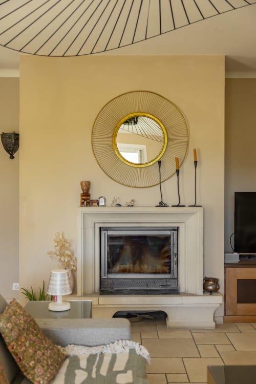 Élégant salon avec cheminée, miroir soleil doré et décoration moderne à la maison d'hôtes Mas Tihou au Beausset