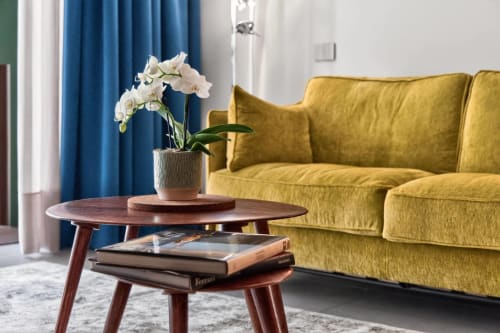 Elegante loft Jenner a Nestco Milano con divano giallo senape, tavolino in legno con orchidea bianca e blu