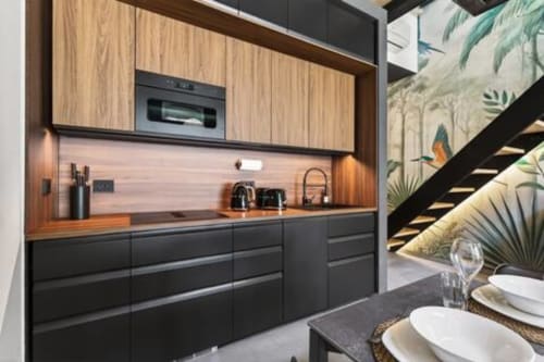 Cucina moderna del Loft Jenner, Nestco Milano, con cabinetry nero, piano di lavoro in legno e elettrodomestici integrati