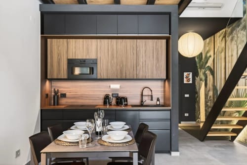 Moderna cucina loft e zona pranzo a Nestco Milano con mobili neri, dettagli in legno e tavolo apparecchiato per due persone