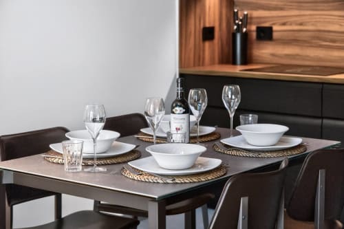 Tavolo elegantemente apparecchiato al The Loft Jenner, Nestco Milano, con bicchieri di vino, ciotole bianche e segnaposti con vista panoramica