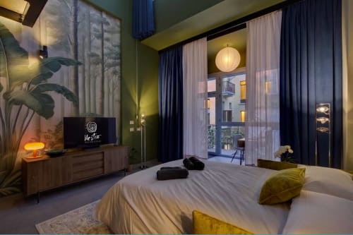 Camera moderna al Nestco Loft Jenner di Milano con pareti verdi, grandi finestre con vista sul giardino, letto con cuscini gialli