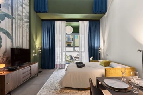 L'appartamento Loft Jenner a Milano presenta una camera moderna con vista sul giardino, tende blu, biancheria bianca e zona pranzo