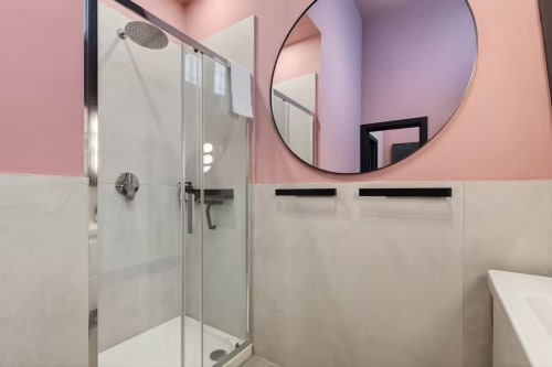Bagno moderno con pareti rosa e bianche, soffione a pioggia, cabina in vetro presso The Loft Jenner, Milano