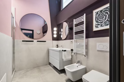 Moderno bagno dell'appartamento The Loft Jenner a Milano, con doppi specchi rotondi, vanità bianca e scaldasalviette