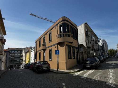 Villa Amber Star em Vila Nova de Gaia com fachada ocre curva, carros estacionados e placa azul de trânsito em rua de calçada