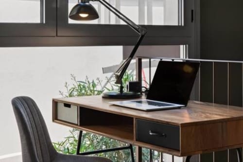 Spazio di lavoro moderno al The Loft Jenner di Milano - scrivania in legno con laptop, sedia ergonomica nera e lampada a sospensione che affaccia sul giardino