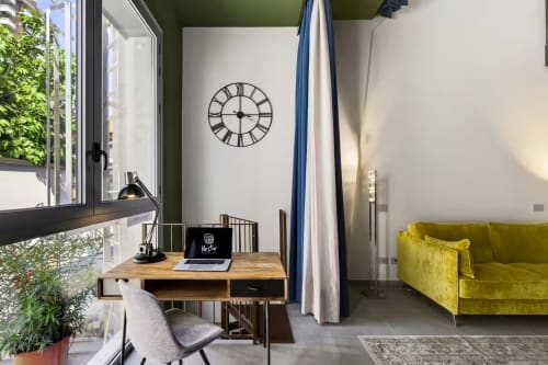 Appartamento Loft moderno Jenner presso Nestco Milano con zona di lavoro, divano giallo, orologio Romano e vista giardino dalle ampie finestre
