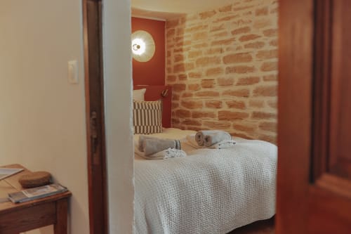 Chambre douillette au Mas Tihou B&B à Le Beausset avec murs en brique apparente, éclairage moderne et vue sur le jardin