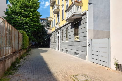 Ingresso della corte milanese con pavimentazione, edificio giallo e portone bianco della rimessa presso The Loft Jenner
