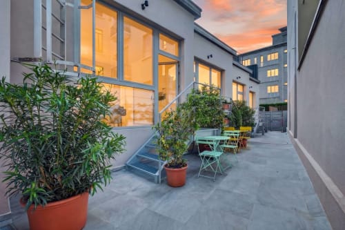 Cortile moderno dell'hotel Nestco Milano con piante in vaso, zone lounge e finestre di vetro illuminate al tramonto