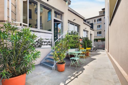 Soleggiata corte con piante in vaso, sedie colorate e tavoli all'Nestco hotel apartment di Milano