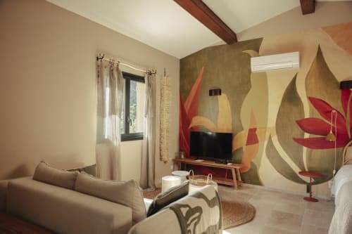 Salon cosy du gîte Mas Tihou au Beausset : canapé beige, télévision et art floral vibrant avec vue sur le jardin