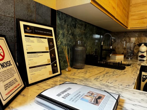 Bancada em mármore na villa Amber Star Rent com cartaz de informações de serviço e acessórios decorativos