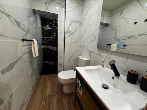 Banheiro moderno na villa Antas Family Retreat com azulejos efeito mármore, cuba branca, vaso sanitário, torneira preta e vidro