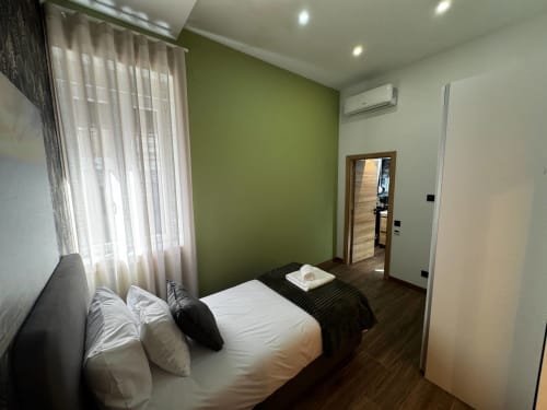 Quarto moderno da Vila Amber Star em Vila Nova de Gaia com parede de destaque verde, cama queen, vista da cidade e banheiro privado