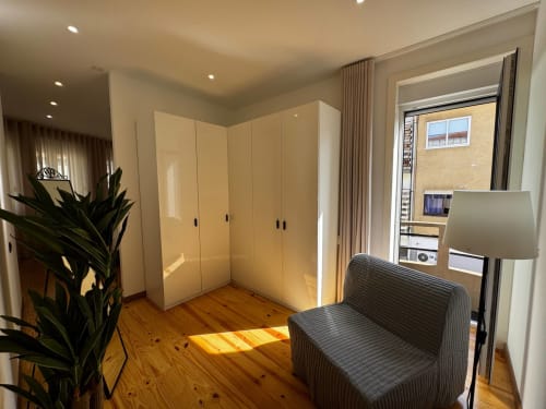 Quarto moderno da villa Amber Star Rent em Vila Nova de Gaia com guarda-roupa creme, assoalho de madeira, mobiliário cinzento e vista cidade