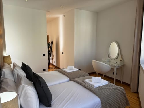 Quarto moderno na Antas Family Retreat da Amber Star Rent em Vila Nova de Gaia com camas geminadas, espelho de penteadeira e vista da cidade.