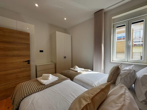 Camas geminadas com roupa branca na villa Antas Family Retreat em Amber Star Rent, Vila Nova de Gaia, com porta de madeira e guarda-roupa