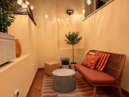 Accogliente salotto con divano in terracotta, piante, tavolino rotondo e calde luci stringa a Roma